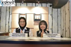 dos mujeres de pie en frente de una cabina con signos en Happy Inn en Yakarta