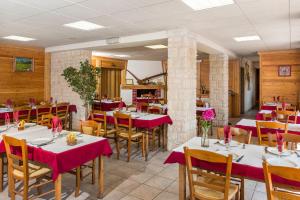 a restaurant with tables and chairs with red table cloth at Hotel restaurant Le Chamois in Ancelle