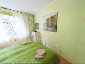 a bedroom with a green bed and a painting on the wall at Ferienwohnungen Ender in Eisenach