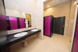 a bathroom with two sinks and two purple stalls at SleepBox Hostel in Taipei