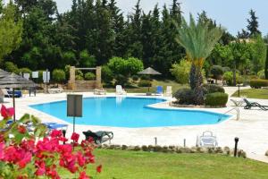 una gran piscina en un complejo con flores rosas en Limnaria Villas Sunny Garden Apartment, en Pafos