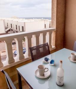 a table with two cups and a bottle on a balcony at La Perla Médano 3 in El Médano