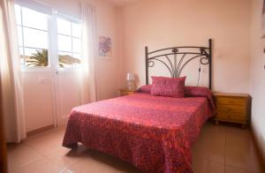 a bedroom with a bed with a red bedspread and a window at Apartamento con ascensor en primera línea in Gran Tarajal
