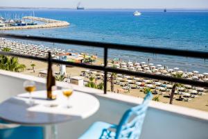 vistas a una playa con sombrillas, mesa y sillas en Krasas Beach Apts, en Lárnaca