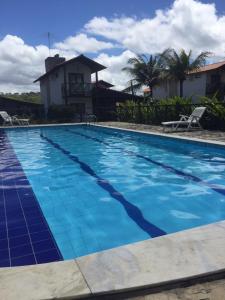 una piscina con acqua blu di fronte a una casa di Casa de Luxo com 3 Suites no Condominio Horizonte da Serra 1 em Gravatá a Gravatá