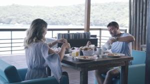 Ein Mann und eine Frau sitzen an einem Tisch und essen in der Unterkunft Caixa D'aço Exclusive Hotel in Porto Belo