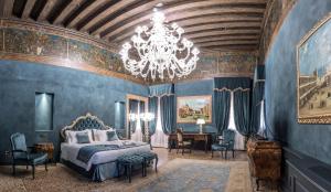ヴェネツィアにあるホテル ナニ モチェニーゴ パレスの青い壁のベッドルーム1室、シャンデリアが備わります。