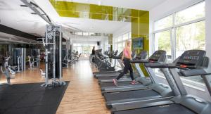 a woman running on treadmills in a gym at Grand Lubicz Uzdrowisko Ustka in Ustka