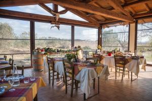 a dining room with tables and chairs and large windows at El Molino Agriturismo in Fonteblanda