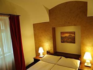 a bedroom with a bed with two lamps and a window at Hotel U Kříže in Prague