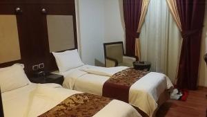 um quarto de hotel com duas camas e uma cadeira em Raoum Inn em Kuwait