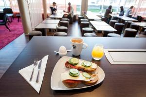 a plate with sandwiches and a cup of coffee on a table at Motel L Hammarby Sjöstad in Stockholm