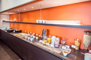 a buffet line in a restaurant with an orange wall at Motel L Hammarby Sjöstad in Stockholm