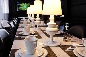 パリにあるホテル イコンの白いランプと皿が置かれた長テーブル