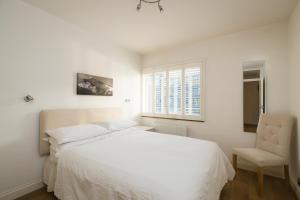 1 dormitorio con 1 cama blanca y 1 silla en Sublime 1 bed flat with Thames view en Londres