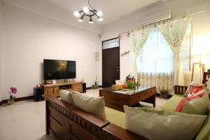a living room with a couch and a tv at Happy Together Guesthouse in Taitung City