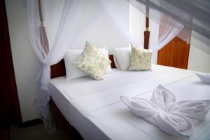 un letto bianco con cuscini e un fiore sopra di BV Residence a Tangalle