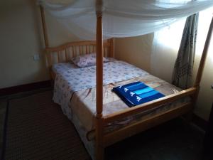 1 dormitorio con cama de madera y dosel en Rwenzori Trekking Homestay, en Nyakalengija