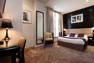 a bedroom with a bed and a desk and a mirror at Hotel Icône in Paris