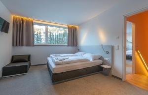 Un dormitorio con una cama y una silla y una ventana. en Riverside Residence Flachau, en Flachau