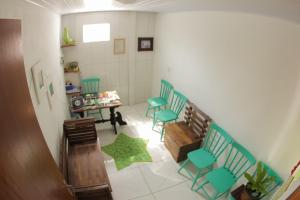 a room with green chairs and a table and a table at Pousada Três Irmãos in Penha