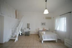 a white bedroom with a bed and a staircase at Seaside Apartments in Adamantas