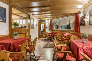 コルティーナ・ダンペッツォにあるホテル オリンピアのテーブルと椅子、赤いテーブルと椅子が備わるレストラン