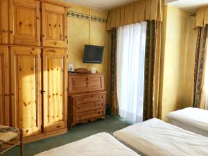 a bedroom with a bed and a dresser at Hotel Olimpia in Cortina dʼAmpezzo