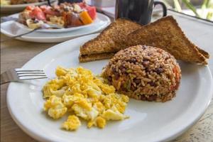 a white plate with scrambled eggs and toast on a table at Hotel Estrella in Managua