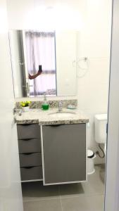 a bathroom with a sink and a mirror and a toilet at Estudio em Palmas do Arvoredo - Gov. Celso Ramos in Governador Celso Ramos
