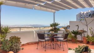 um pátio com uma mesa, cadeiras e vasos de plantas em Casa Alta Mojacar Pueblo em Mojácar