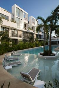 a swimming pool with lounge chairs in front of a building at Anah Suites Tulum by Sunest in Akumal