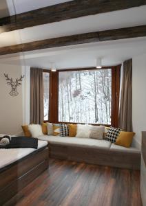 a living room with a large couch in front of a window at Apartmán 16 Romantika Chopok Juh Tále in Tale