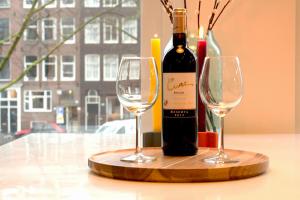 Una botella de vino y dos copas de vino en una mesa en Da Costa Suite, en Ámsterdam 7 fotos más