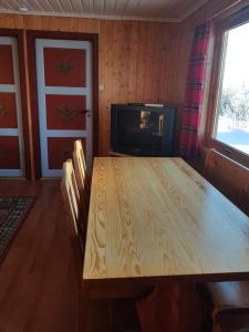 Knutebu Two-Bedroom Cottage في جيلو: غرفة طعام مع طاولة خشبية وتلفزيون