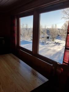 a room with a window looking out at a snow covered yard at Knutebu Two-Bedroom Cottage in Geilo