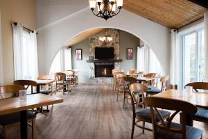 a restaurant with tables and chairs and a fireplace at Hôtel Chéribourg in Magog-Orford