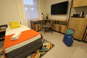 1 dormitorio con 1 cama y escritorio con TV en Apartamenty Garbary 3, en Bydgoszcz