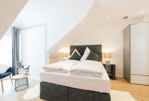 1 dormitorio con 1 cama con sábanas y almohadas blancas en Unique Inn, en Schöngeising