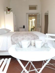 Una mesa blanca con dos tazas junto a una cama. en Anna Home in Chiaia en Nápoles