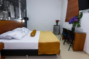 um quarto com uma cama, uma mesa e cadeiras em Hotel Sauces del Estadio em Medellín