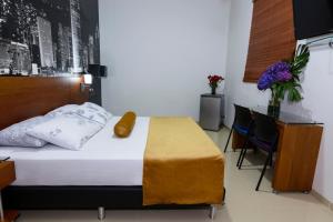 a bedroom with a bed and a table and chairs at Hotel Sauces del Estadio in Medellín