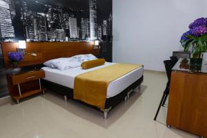 a bedroom with a large bed with a night stand at Hotel Sauces del Estadio in Medellín