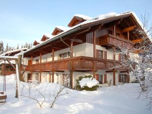 ein großes Holzgebäude mit Schnee auf dem Boden in der Unterkunft Apartments Lettenmaier in Oberried