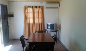 ein Esszimmer mit einem Tisch und einem TV in der Unterkunft Cabañas los Cactus in San Rafael