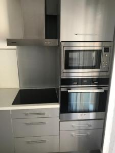 una cocina con electrodomésticos de acero inoxidable y armarios blancos en Boost Your Immo Vars Le Regain 6, en Vars