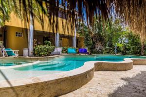 a swimming pool in front of a building with palm trees at Ocean View Villas in Kralendijk