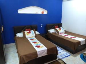 two beds in a room with a blue wall at Kenzy Palace Luxor in Luxor