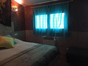 1 dormitorio con 1 cama y una ventana con cortinas azules en Apartamento Ginebra Deluxe, en Sierra Nevada