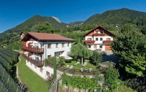 une vue aérienne d'une maison avec des montagnes en arrière-plan dans l'établissement Schwarzplatterhof, à Merano